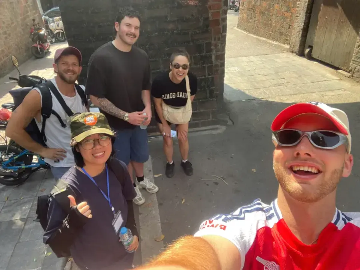 Group of travelers on a private walking tour in Hanoi taking a selfie with a local guide in the Old Quarter